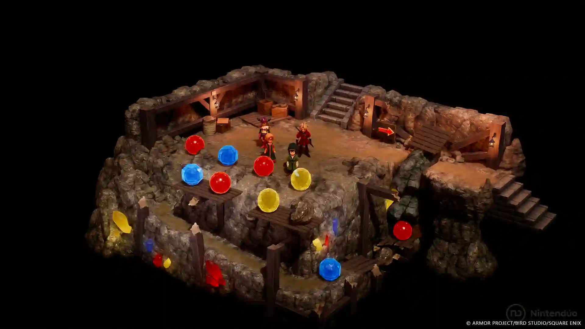 Dragon Quest VII Reimagined: diorama de una mazmorra subterrránea con paredes rocosas donde los personajes se mueven entre orbes de colores rojo, azul y amarillo.