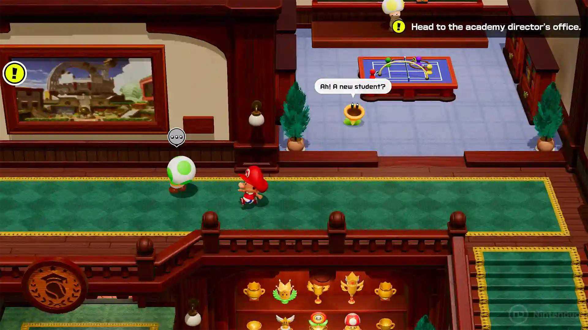 Mario Tennis Fever – Mario camina por un pasillo de la academia con alfombra verde hablando con un Toad verde, mientras en la planta baja se exhiben trofeos de tenis y el juego muestra mensajes como “Head to the academy director's office” y “Ah! A new student?”.