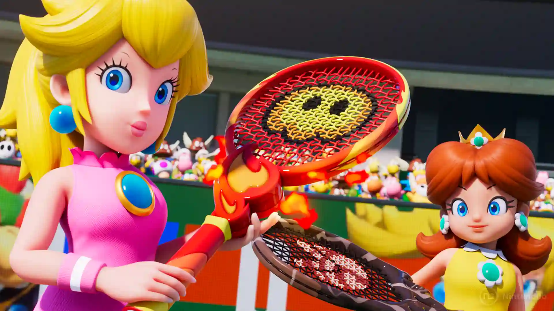 Mario Tennis Fever – primer plano de la Princesa Peach con vestido rosa levantando su raqueta decorada con una carita sonriente, mientras Daisy con vestido amarillo se acerca desde el fondo; ambas se preparan para un partido ante el público del estadio.