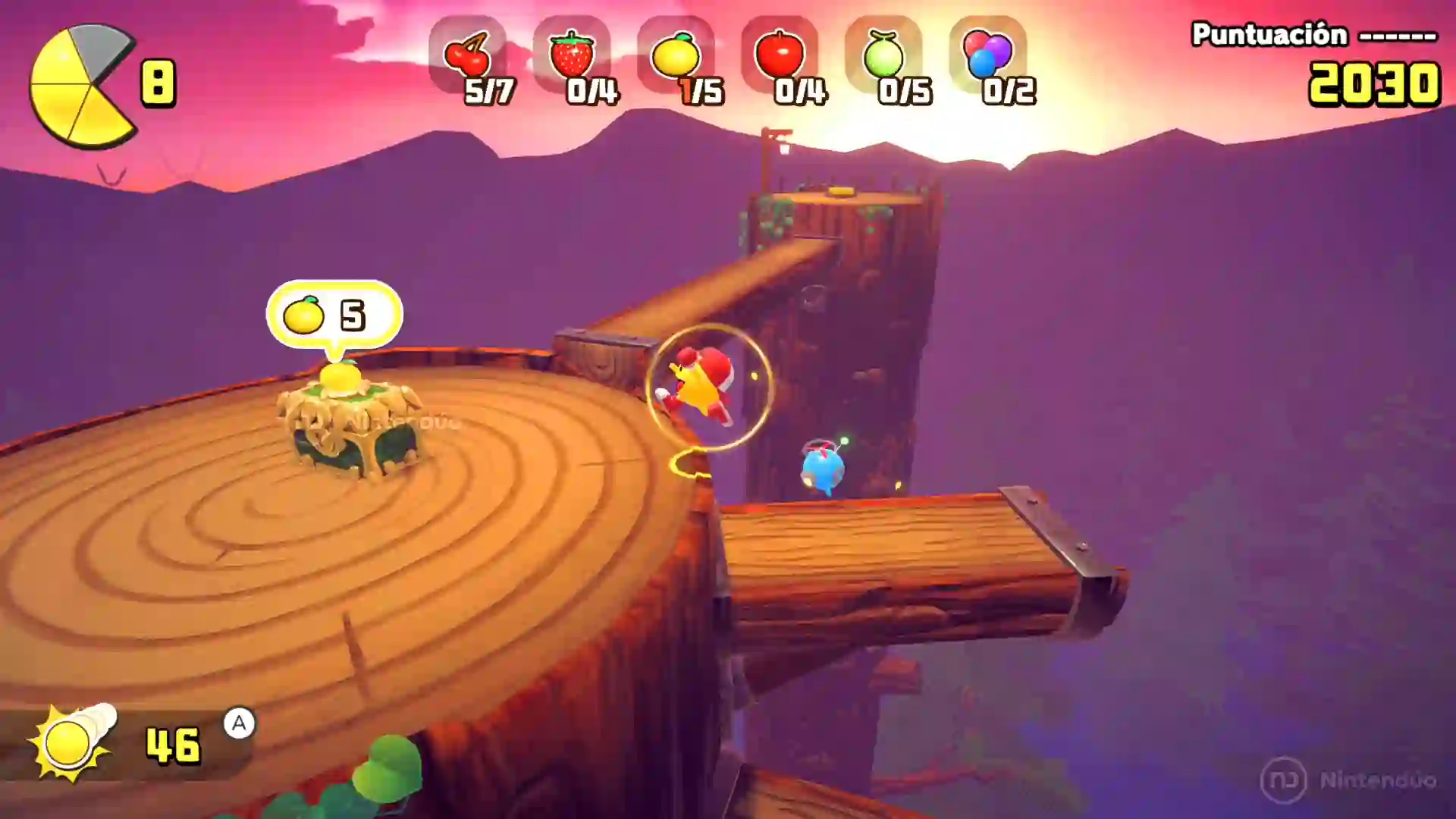 Captura de Pac‑Man World 2 Re‑Pac mostrando a Pac‑Man en una plataforma circular de madera con contadores de frutas y puntuación en la interfaz, frente a un paisaje al atardecer.