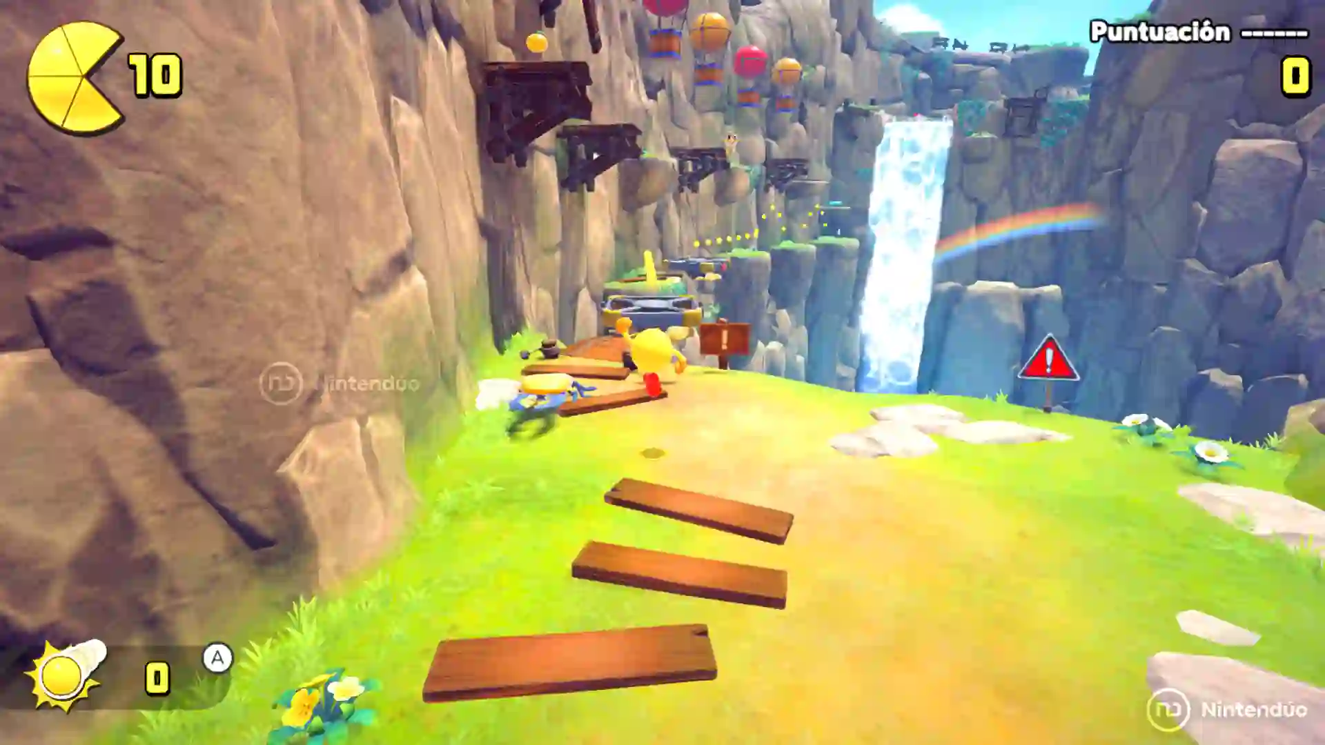 Escena de Pac‑Man World 2 Re‑Pac en un cañón con pasarelas de madera frente a una cascada, donde Pac‑Man debe cruzar saltando y recolectar objetos.