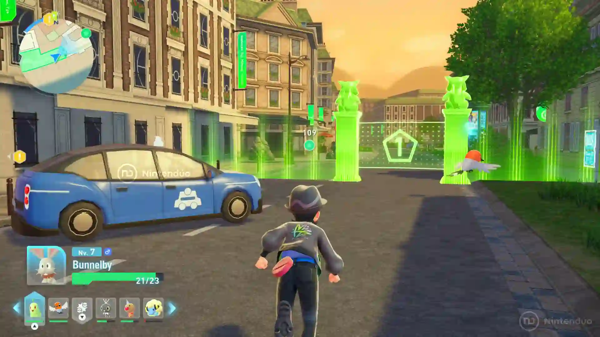 El protagonista de Leyendas Pokémon Z-A para Nintendo Switch 2 corre por una calle de Ciudad Luminalia junto a un Bunnelby nivel 7 mientras se acerca a un circuito de entrenamiento marcado por columnas verdes luminosas y flechas.