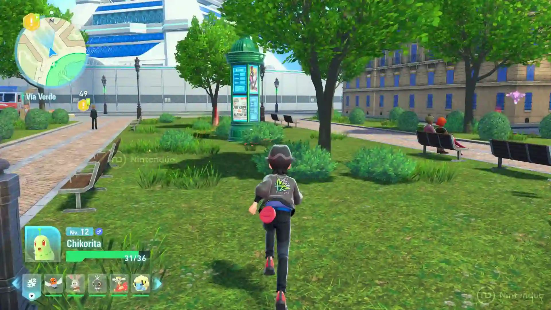 El jugador explora un parque verde con árboles y bancos en Ciudad Luminalia en Leyendas Pokémon Z-A para Nintendo Switch 2, acompañado por su Chikorita de nivel 12 en el equipo.