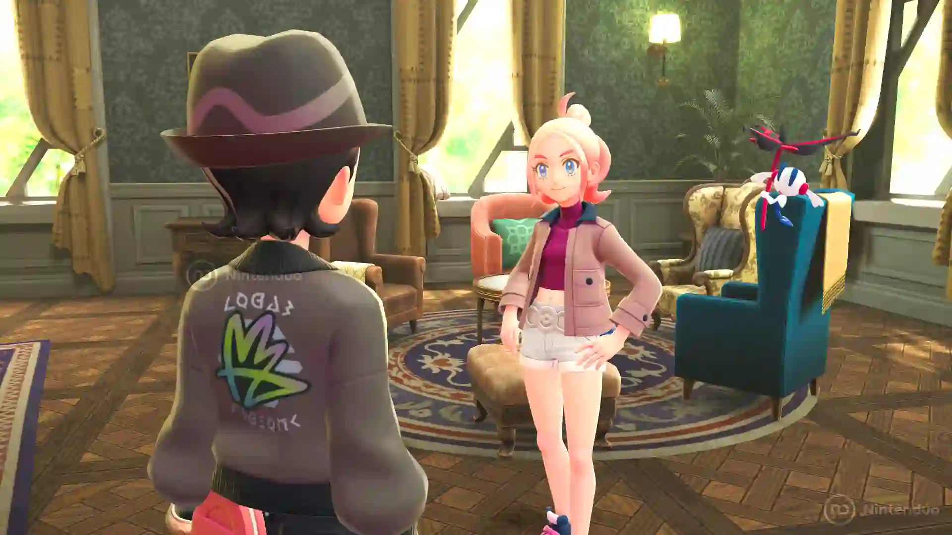 Escena de Leyendas Pokémon Z-A para Nintendo Switch 2 en la que la entrenadora rubia conversa con el protagonista en un salón elegante, con el jugador vistiendo una chaqueta con logotipo en la espalda.