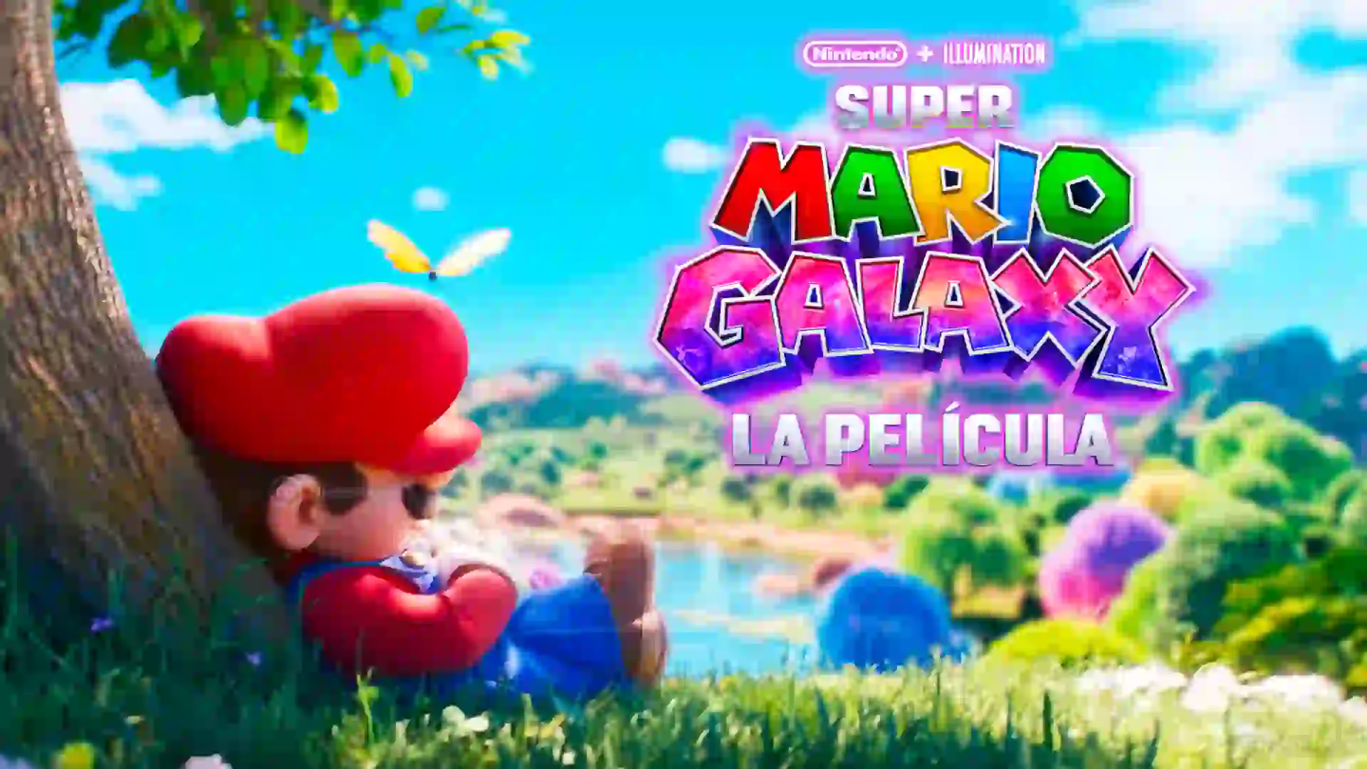 Mario descansa apoyado en un ĂĄrbol en un prado junto a un lago mientras el colorido logo de Super Mario Galaxy La PelĂcula destaca en el cielo.