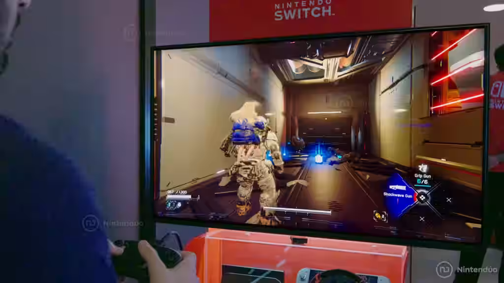 Pantalla de televisión mostrando gameplay de Pragmata con personajes explorando interior de nave espacial futurista con iluminación neón roja