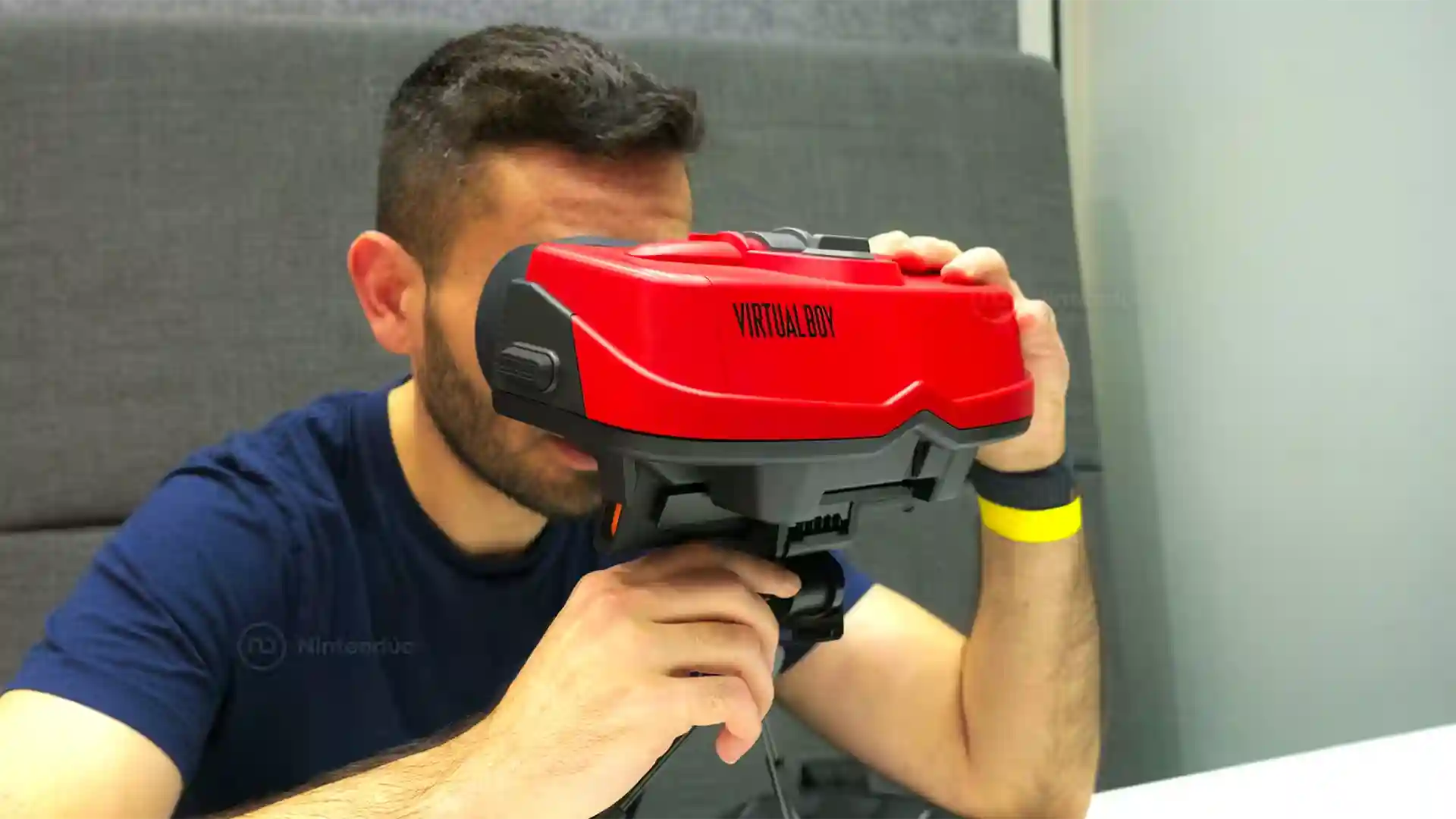 Persona usando las gafas de realidad virtual Virtual Boy de Nintendo con diseño rojo y negro característico